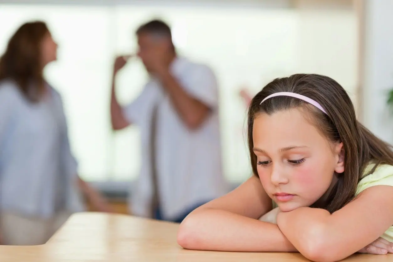 Sad girl watching parents argue.