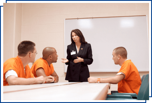 A woman talking to inmates in an orange jumpsuit.