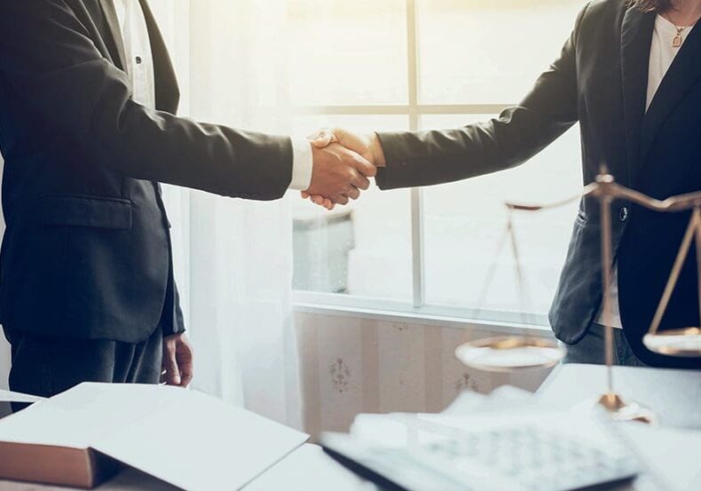 Two lawyers shaking hands in an office.